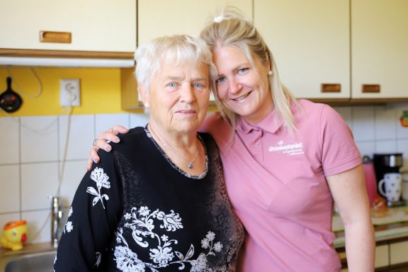 Alltagsbegleitung mit Herz Ältere Frau und junge Frau stehen in einer Küche, beide lächeln freundlich.